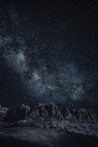 Stunning view of the starry night sky with rocky mountain silhouettes.